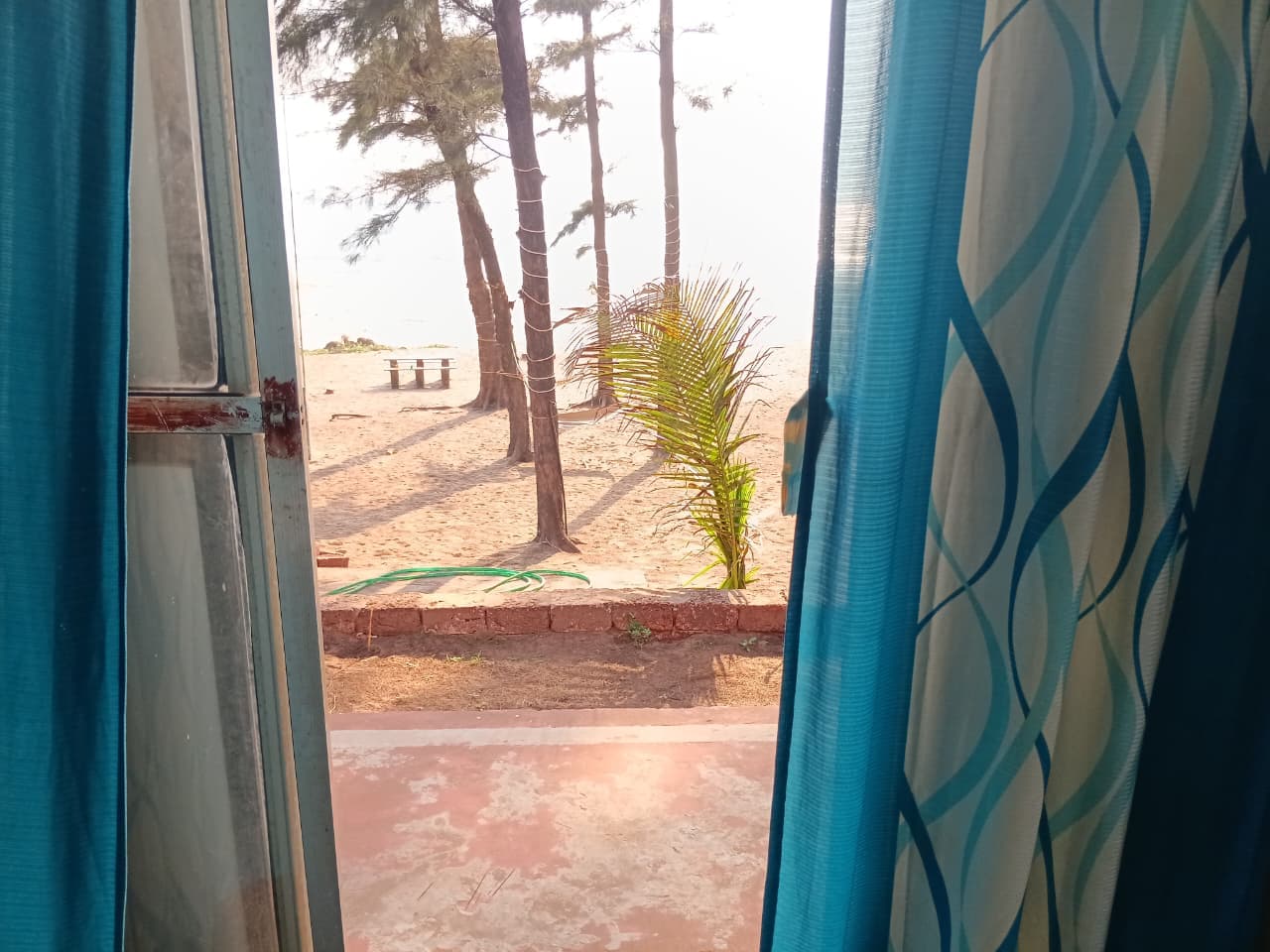 Sea-facing view through blue curtains at The Red Stones Resort